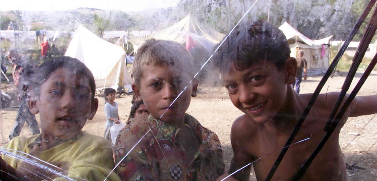 Romska djeca igraju se ispred starog autobusa u kampu na sjeveru kosovskog grada Đakovica u julu 1999. (Foto: AP Photo/Pier Paolo  Cito)