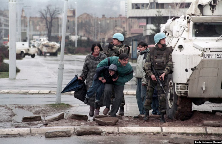 Stanovnici Sarajeva skrivaju se od snajperske vatre iza oklopnog vozila UNPROFOR-a u centru Sarajeva, 1993.
