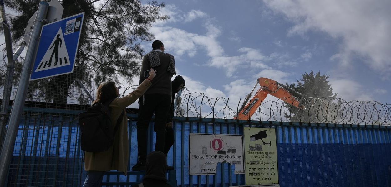 Ljudi posmatraju rušenje kompleksa UNRVA-e, agencije Ujedinjenih nacija koja pruža pomoć palestinskim izbjeglicama, u Istočnom Jerusalimu (Foto: AP photo/Mahmoud Illean)