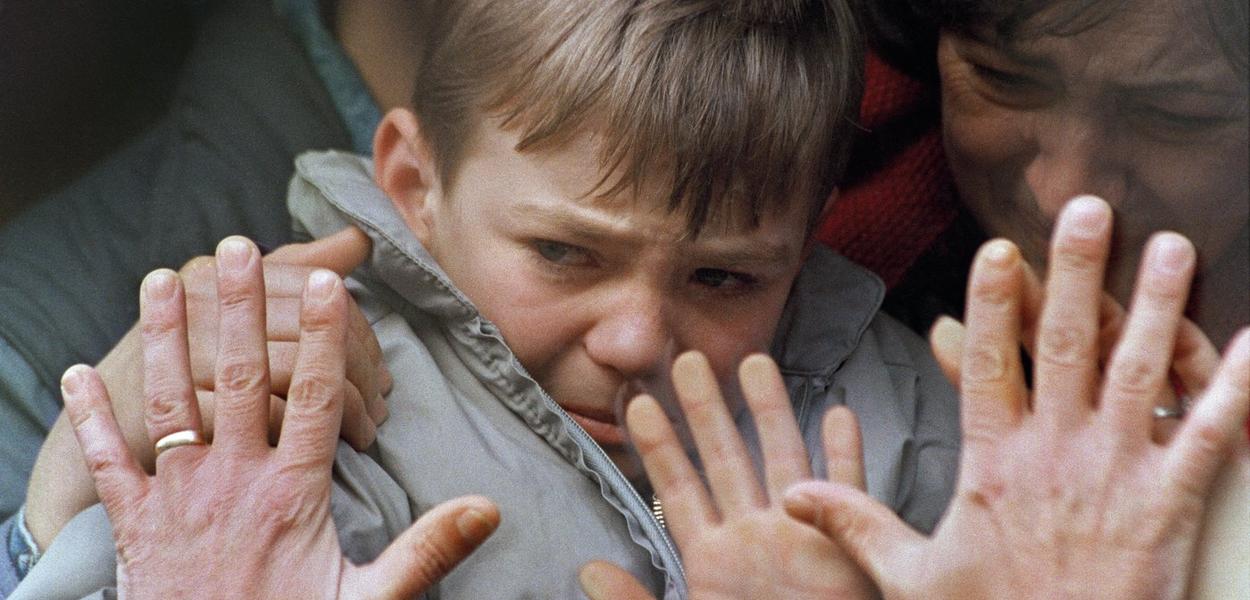Očeve ruke pritiskaju prozor autobusa koji prevozi njegovog uplakanog sina i ženu na sigurno iz opkoljenog grada Sarajeva, Bosna, tokom rata u Bosni, 10. novembra 1992.  (Foto: AP Photo/Laurent Rebours, File)