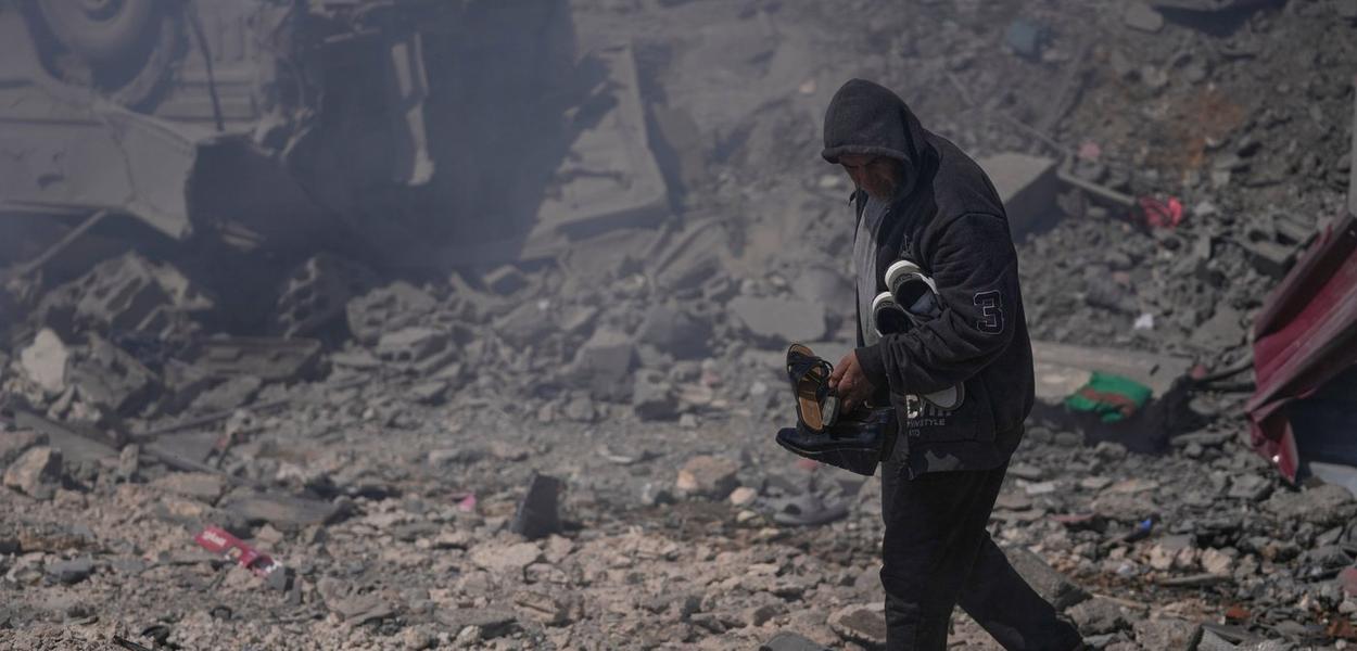 Muškarac nosi cipele iz njegove uništene kuće u izraelskom vazdušnom napadu, Liban, 8. mart 2026 (Foto: AP Photo/Mohammed Zaatari)