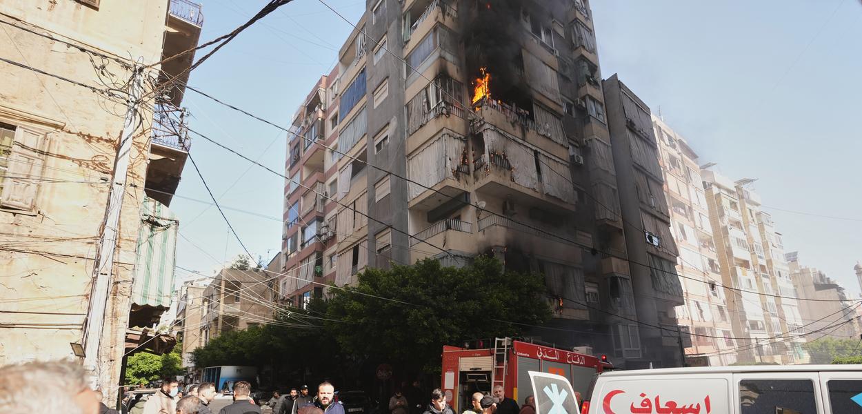 Ljudi se evakuišu pored ambulantnog vozila dok se plamen diže iz stambene zgrade nakon izraelskog vazdušnog napada u centralnom Bejrutu, Liban, u srijedu, 18. marta 2026. (Foto: AP foto/Hassan Ammar)