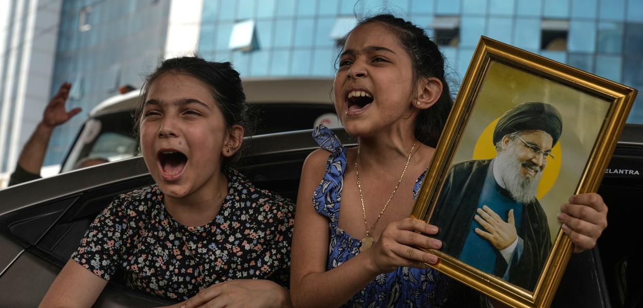 Dvije djevojke skandiraju slogane dok jedna drži sliku pokojnog lidera Hezbolaha Hasana Nasralaha u Dahijehu, južnim predgrađima Bejruta, Liban, u petak, 17. aprila 2026. godine, nakon primirja između Izraela i Hezbolaha (Foto: AP foto/Bilal Hussein)